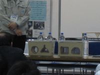 水槽の細砂の中に、円形、三角形、四角形、半円形を置き、細砂の上に板を敷きペットボトルに水を入れたおもりを置きます。